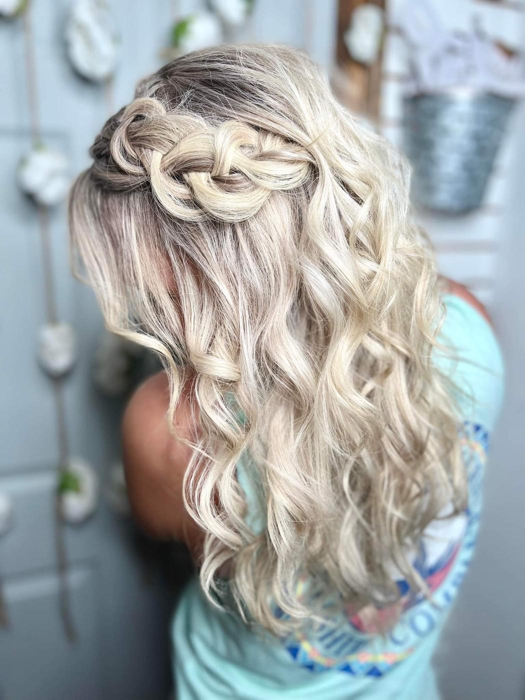 A blonde half up style with a braid across the crown and curled lengths below.